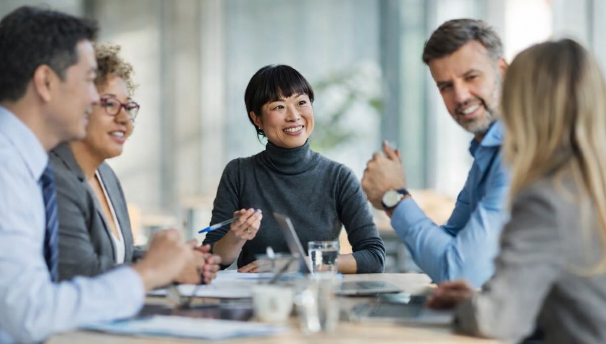 A female executive and her team members seated together in a meeting, listening and speaking during a group discussion