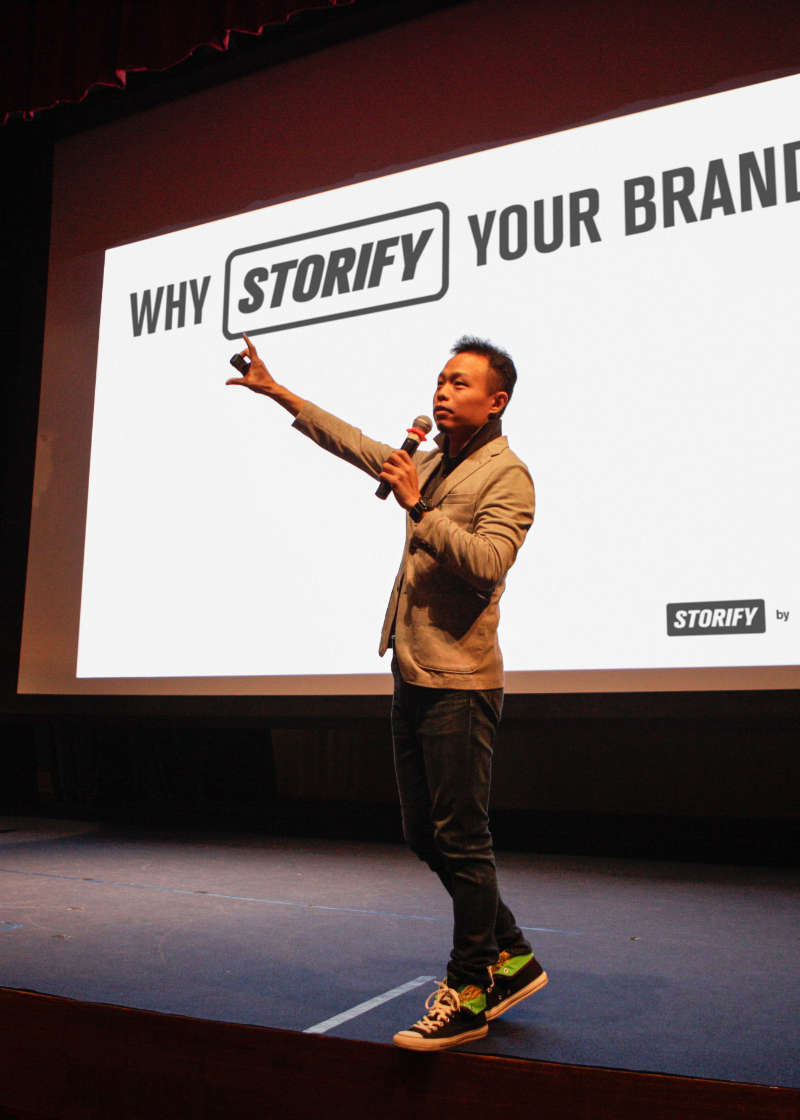 Ellery Ng speaking on stage during a brand storytelling presentation, displaying the real-life skills he bases his coaching on today.